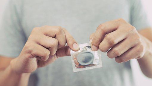 Foto von Händen, die eine Kondompackung öffnen